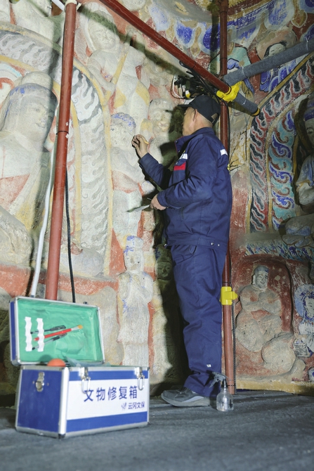 文物修復人員正在修復佛像。云岡石窟景區供圖
